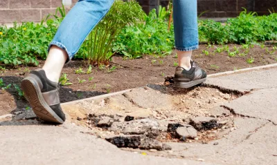 Person stepping over hole in sidewalk.