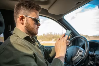Man sitting in driver's seat looking at cell phone.