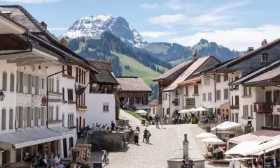 View of pedestrian plaza in Swiss village with Alps in background.