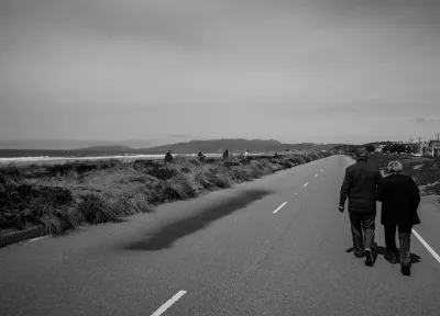 Black and white photos of couple walking on Great Highway road in San Francisco on the water during the pandemic when the road was closed to vehicular traffic.