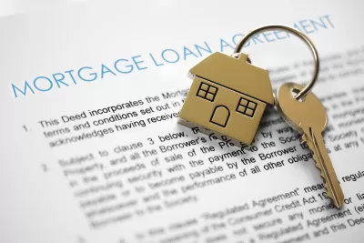 Close-up on mortgage application terms and house-shaped gold keychain with gold key on it.