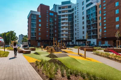 High-rise modern apartment buildings with green space in front courtyard with outdoor exercise equipment.