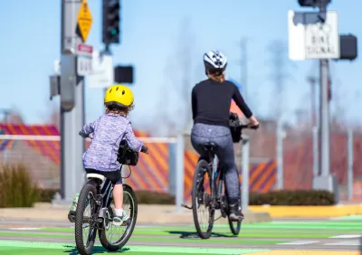 Mother and child on bicycles riding on green dedicated bike lane