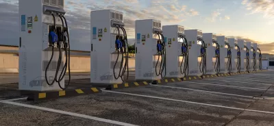 Row of white electric vehicle chargers in an outdoor parking lot.