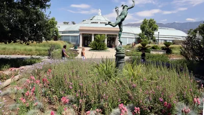 Glass-topped conservatory building with bronze statue in foreground at Los Angeles County Arboretum and Botanic Garden