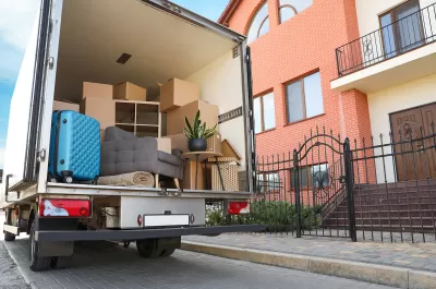 Moving truck with open back door with furniture and a blue suitcase visible inside.