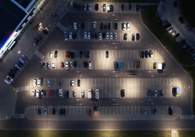 Bird's eye view of half full parking lot at night.