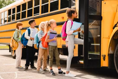 Children boarding yellow school bus.