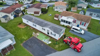 Aerial view of manufactured home being dropped off or moved by red truck in mobile home park