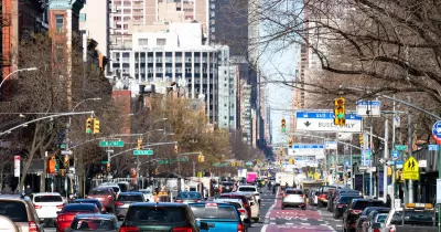 Busy New York city street with red painted bus-only lane on right.