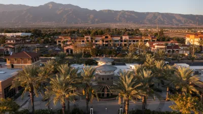 Aerial view of Rancho Cucamonga, California with suburban commercial center and large palm trees at sunset with mountains in background.