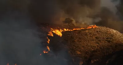 Line of wildfire moving across dry hillside in Malibu, California during 2018 Woolsey fire.