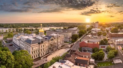 Aerial view of Trenton, New Jersey with gold state capitol down in foreground and golden hour sky.