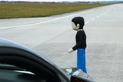 Child-sized pedestrian crash test dummy in front of car being tested