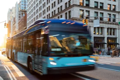 Blue and green city bus blurred in transit on New York City street.