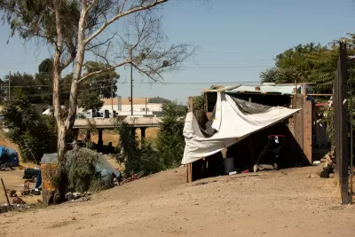 Makeshift shelter built by unhoused people on hillside overlooking freeway in Stockton, California.