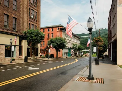 Street with historic buildings and American flag hanging from lamppost in downtown Hinton, West Virginia.