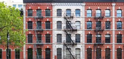 Brick New York City apartment buildings with fire escapes.