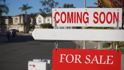 Close-up on red and white "Coming Soon" and "For Sale" signs in front of single-family homes on sunny day.