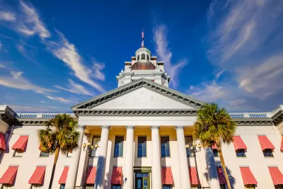 White and peach Florida state capitol building with palm trees in front in Tallahassee, Florida.