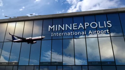 Sign on glass building for Minneapolis International Airport with airplane landing reflected in building.