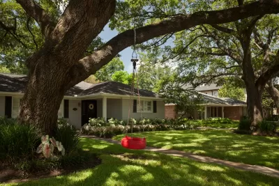 Small house with a red tire swing in front yard in Houston, Texas.