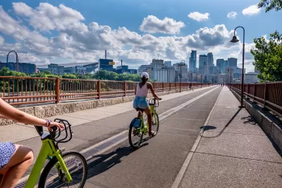 People on bike share bikes on bridge with Minneapolis, Minnesota skyline in background
