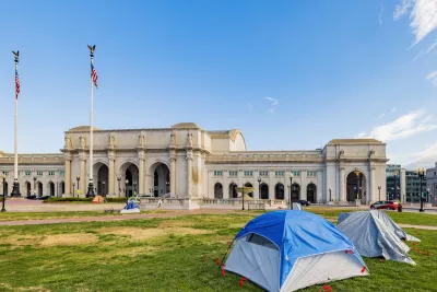 Several tents set up by unhoused residents on green lawn in front of neoclassical Union Station building in Washington D.C.
