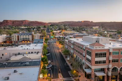 Aerial view of wide street in St. George, Utah at dusk with red rock mountains in background.