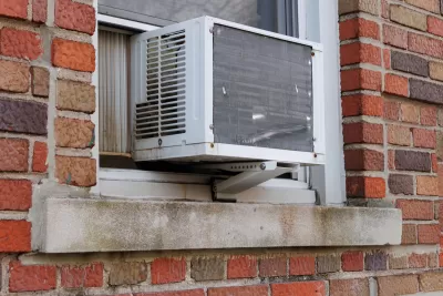 Close-up of window-mounted air conditioning unit on outside of red brick building