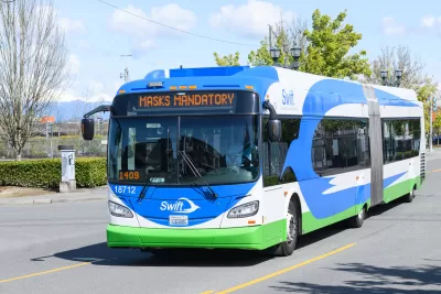 Blue and white bus driving toward the camera with a white logo of a bird that says Swift on the front..