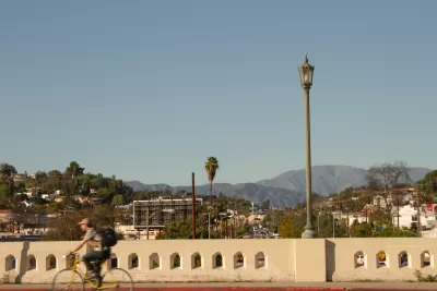 One cyclist on yellow bike crossing vintage concrete bridge in East Hollywood, Los Angeles, California.