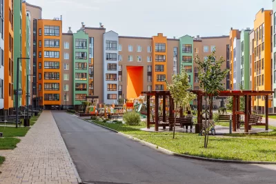 Colorful seven-story apartment buildings around a grasy courtyard with wooden gazebos.