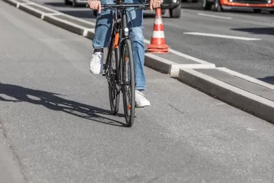 Close-up of person on road bike riding on protected bike lane separated by concrete curb from street.