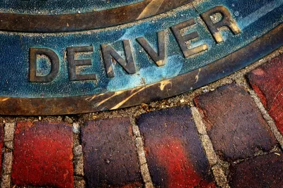 Close-up of Denver title on manhole cover in brick sidewalk or street.