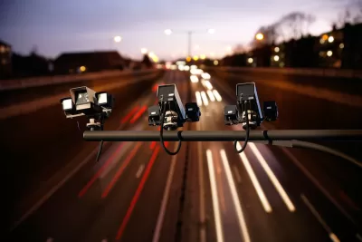 Three speed cameras aimed down at a busy freeway with blurred traffic at twilight.