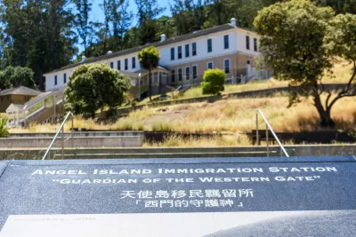 Close-up of plaque at Angel Island Immigration Station, California with historic building in background.