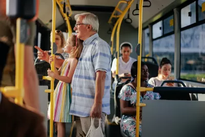 Elderly man and granddaughter standing on public bus.