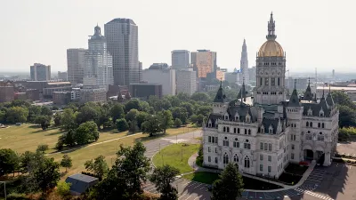 Connecticut state capitol with gold dome and modern office buildings in background in Hartford, CT.