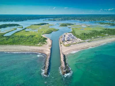 Aerial view of canal cut into beach in Charlestow, Rhode Island with boats parked in sand.