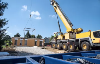 Modular home under construction with crane dropping in components.