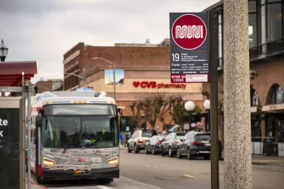 Close-up of white and red Muni sign at bus stop on Polk Street in San Francisco, California with blurred bus in background.