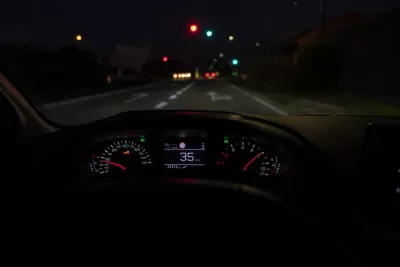 Close-up of car dashboard with speedometer at 35 on roadway at night.