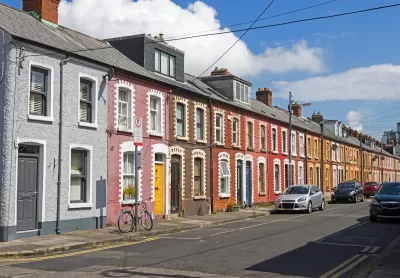 Cars parked along a narrow street with colorful two-story houses in Dublin, Ireland.