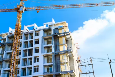 Multistory apartment building under construction with yellow crane.