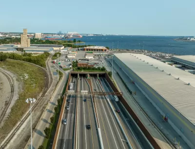 Aerial view of an eight-lane highway tunnel with the harbor in the background.