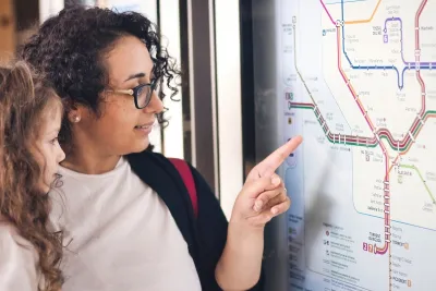 Woman and young girl looking at subway map, woman pointing.
