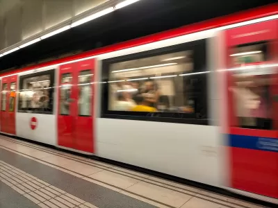 Red and white Barcelona Metro train passing through station.