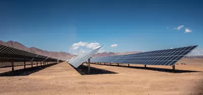 Rows of photovoltaic solar panels in the Nevada desert with mountains in background.