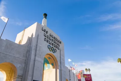 Close-up of Los Angeles Memorial Coliseum entrance arch with title and Olympic rings.